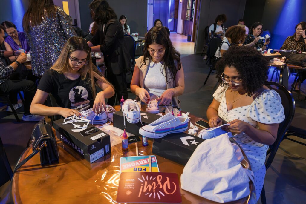 Women customize Converse shoes during a creative workshop indoors.