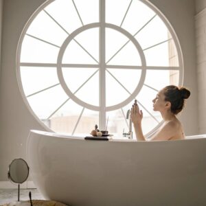 Serene scene of a woman enjoying a relaxing bath by a large window, promoting self-care and tranquility.